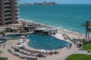 Um resort com uma piscina grande, acesso à praia e vista para o oceano.