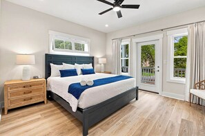 Ein Schlafzimmer mit einem Bett, Nachttischen, einem Deckenventilator und Blick ins Freie.