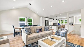 A modern living room with a sofa, coffee table, and dining area. - Out of Office OBX | Private Pool, Hot Tub, Dog Friendly, and Community Pool (Corolla)