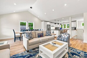 Ein modernes Wohnzimmer mit Sofa, Couchtisch und Essbereich.
