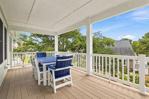 Eine überdachte Veranda mit Tisch und Stühlen, weißen Geländern und Blick auf eine Wohngegend.