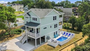A multi-story house with a front deck, a swimming pool, and a covered patio area. - Out of Office OBX | Private Pool, Hot Tub, Dog Friendly, and Community Pool (Corolla)