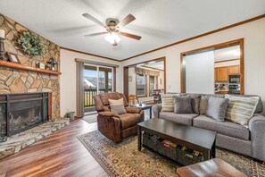 A living room with a fireplace, a ceiling fan, a sofa, and a coffee table.