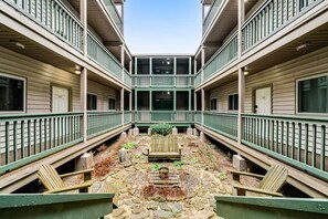 A courtyard with a central seating area, surrounded by balconies with railings.