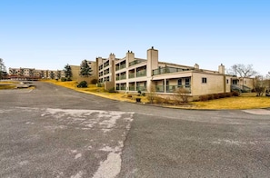 Exterior view of the multi-level residential complex with tiered balconies and paved driveway. - Beech Mountain Condo | Pool, Hot Tub + Fireplace (Beech Mountain)