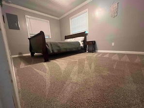 A bedroom with a bed, a nightstand, and a window with blinds. - Tranquil Riverfront Retreat (Depauw)