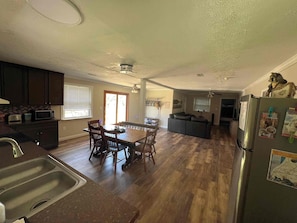 A spacious kitchen with a dining area, wooden flooring, and a refrigerator with magnets. - Tranquil Riverfront Retreat (Depauw)