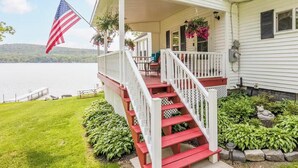 A house with a porch, a flag, and a view of a lake.