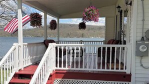 A covered porch with a red and white railing, a welcome sign, and hanging flower baskets.