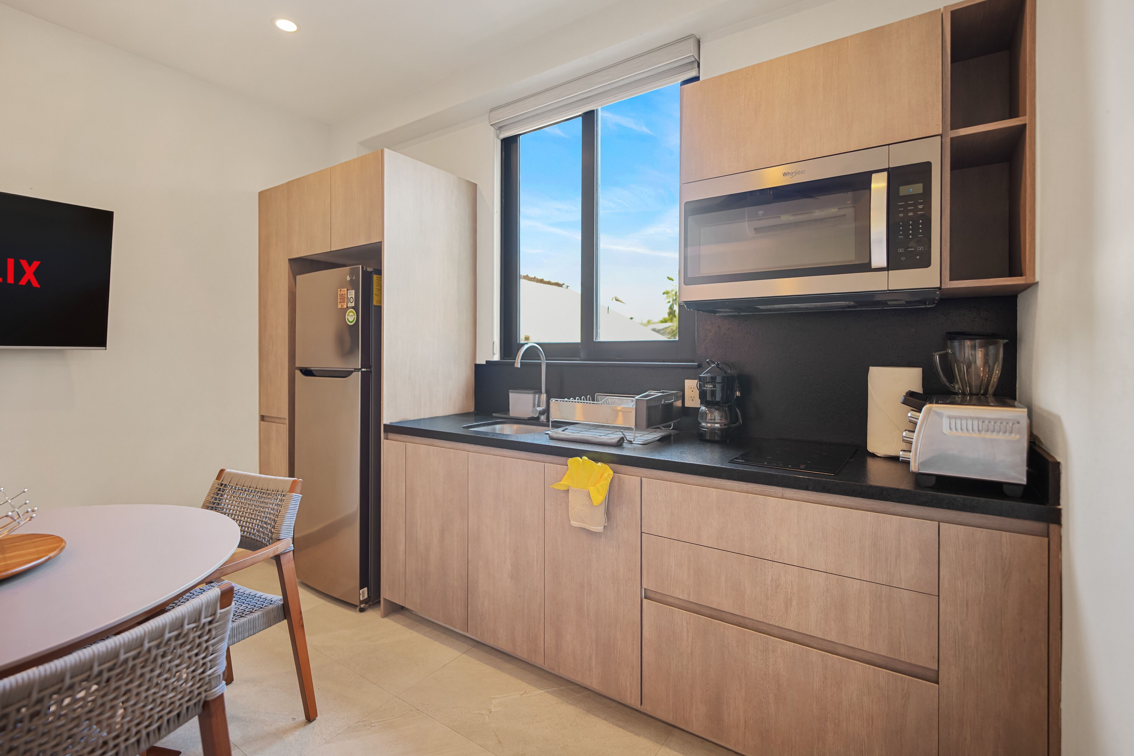 A modern kitchen with wooden cabinets, a built-in microwave, and a stainless steel refrigerator.