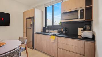 A modern kitchen with wooden cabinets, a built-in microwave, and a stainless steel refrigerator.