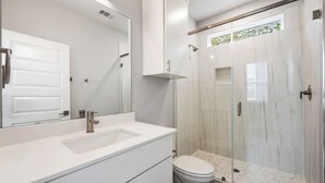 Un baño moderno con un espejo grande, un lavamanos y una cabina de ducha.