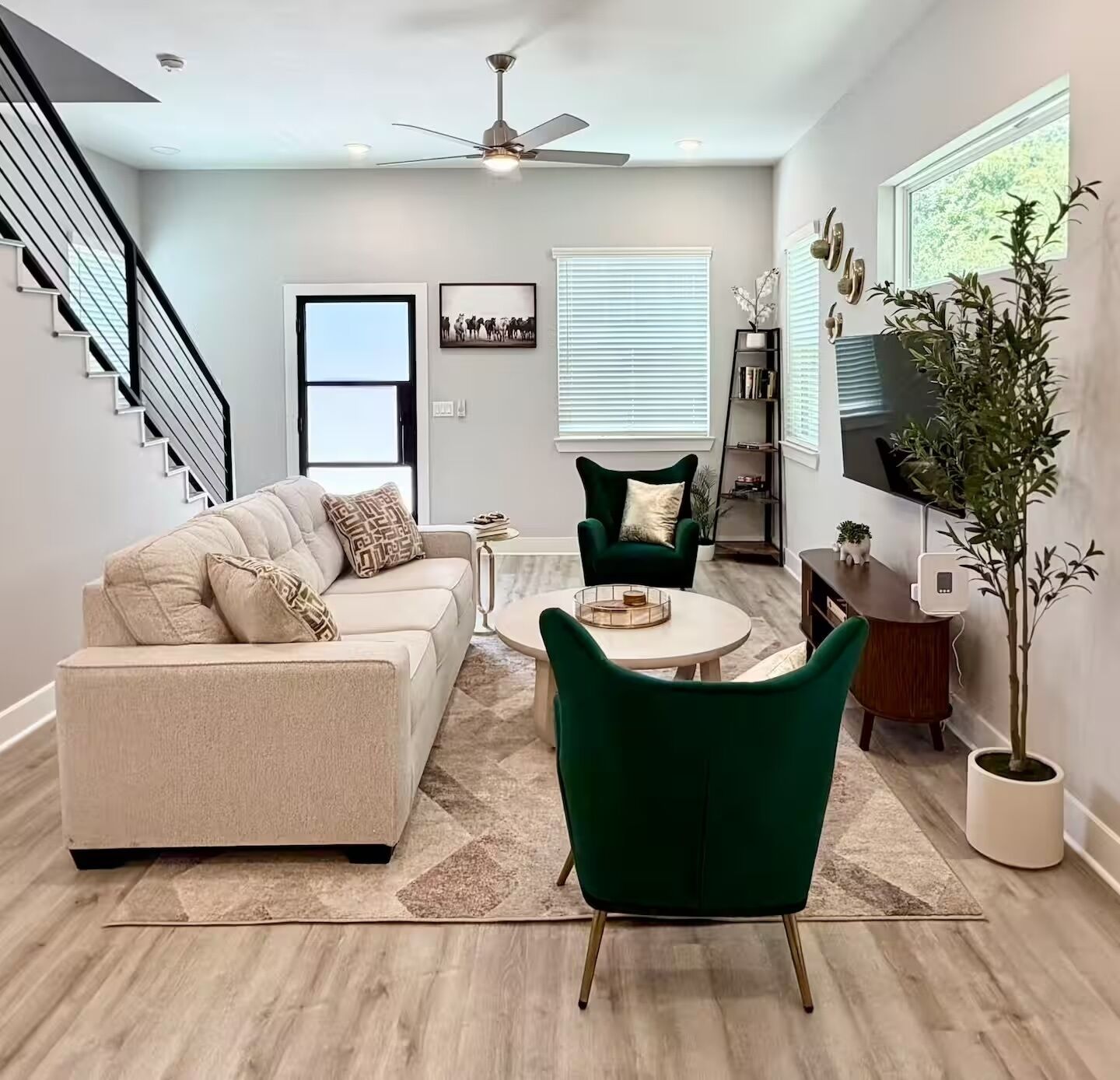 A modern living room with a sofa, a green armchair, a coffee table, a TV, and a staircase.