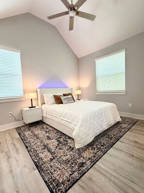 Ein Schlafzimmer mit einem Bett, Nachttischen, einem Teppich und einem Deckenventilator.