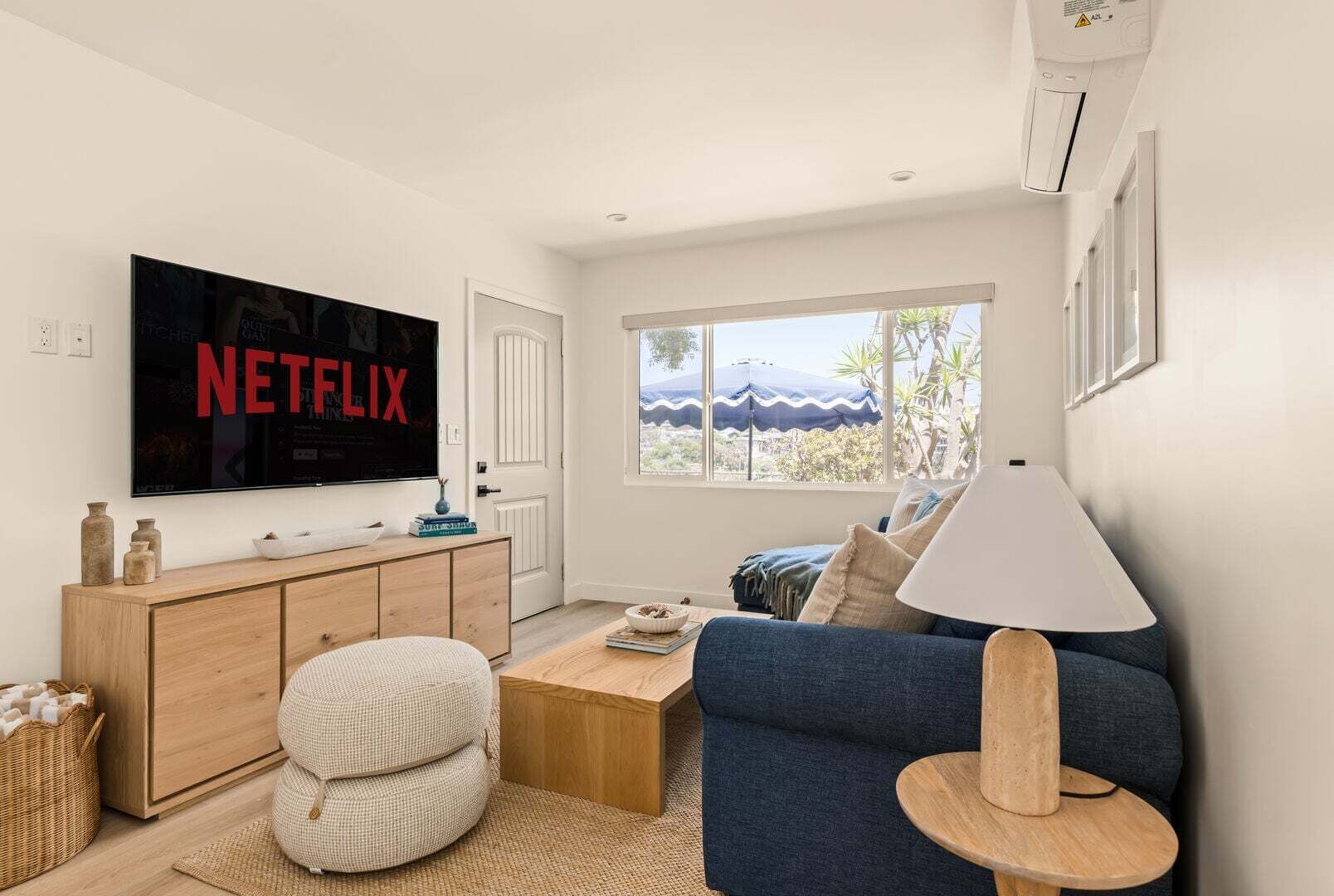 Una sala de estar moderna con un televisor de pantalla plana, un sofá, una mesa de centro y una lámpara.