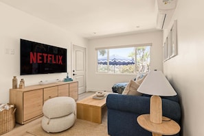 Una sala de estar moderna con un televisor de pantalla plana, un sofá, una mesa de centro y una lámpara.
