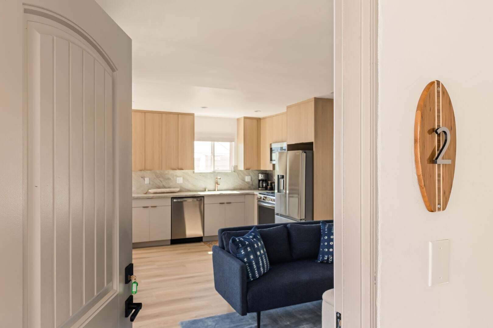 A modern kitchen with wooden cabinets, a built-in oven, and a stainless steel refrigerator.