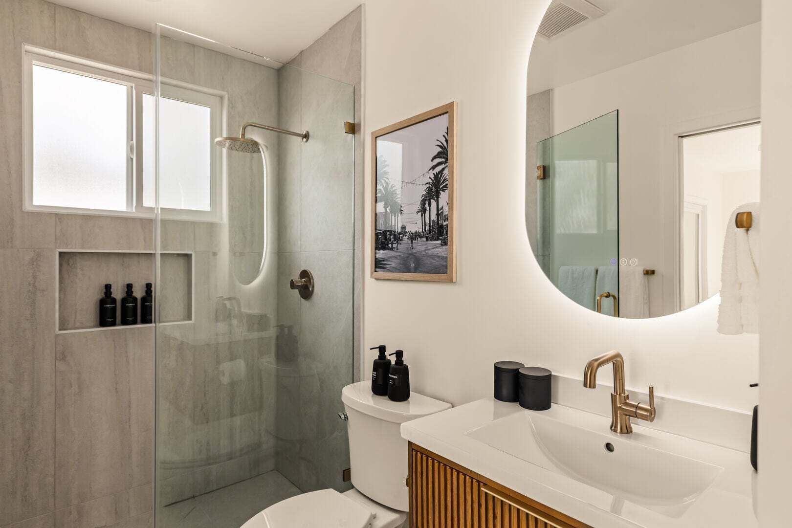 Une salle de bain moderne avec une douche à parois de verre, des toilettes, un lavabo avec un meuble-vasque et un grand miroir.