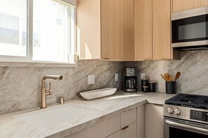 Eine moderne Küche mit Marmorarbeitsplatte, Edelstahlgeräten und Holzschränken.