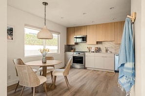 Eine moderne Küche mit Holzschränken, Edelstahlgeräten und einem Essbereich mit Korbstühlen.