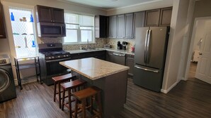A modern kitchen with a central island, stainless steel appliances, and wooden flooring. - The Hideaway Walk to Falls W/D Sleeps 8 (Niagara Falls)