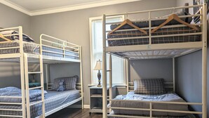 A room with bunk beds, a small table with a lamp, and a window with blinds. - The Hideaway Walk to Falls W/D Sleeps 8 (Niagara Falls)