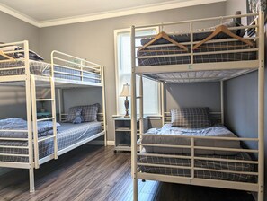 A room with bunk beds, a small table with a lamp, and a window with blinds. - The Hideaway Walk to Falls W/D Sleeps 8 (Niagara Falls)