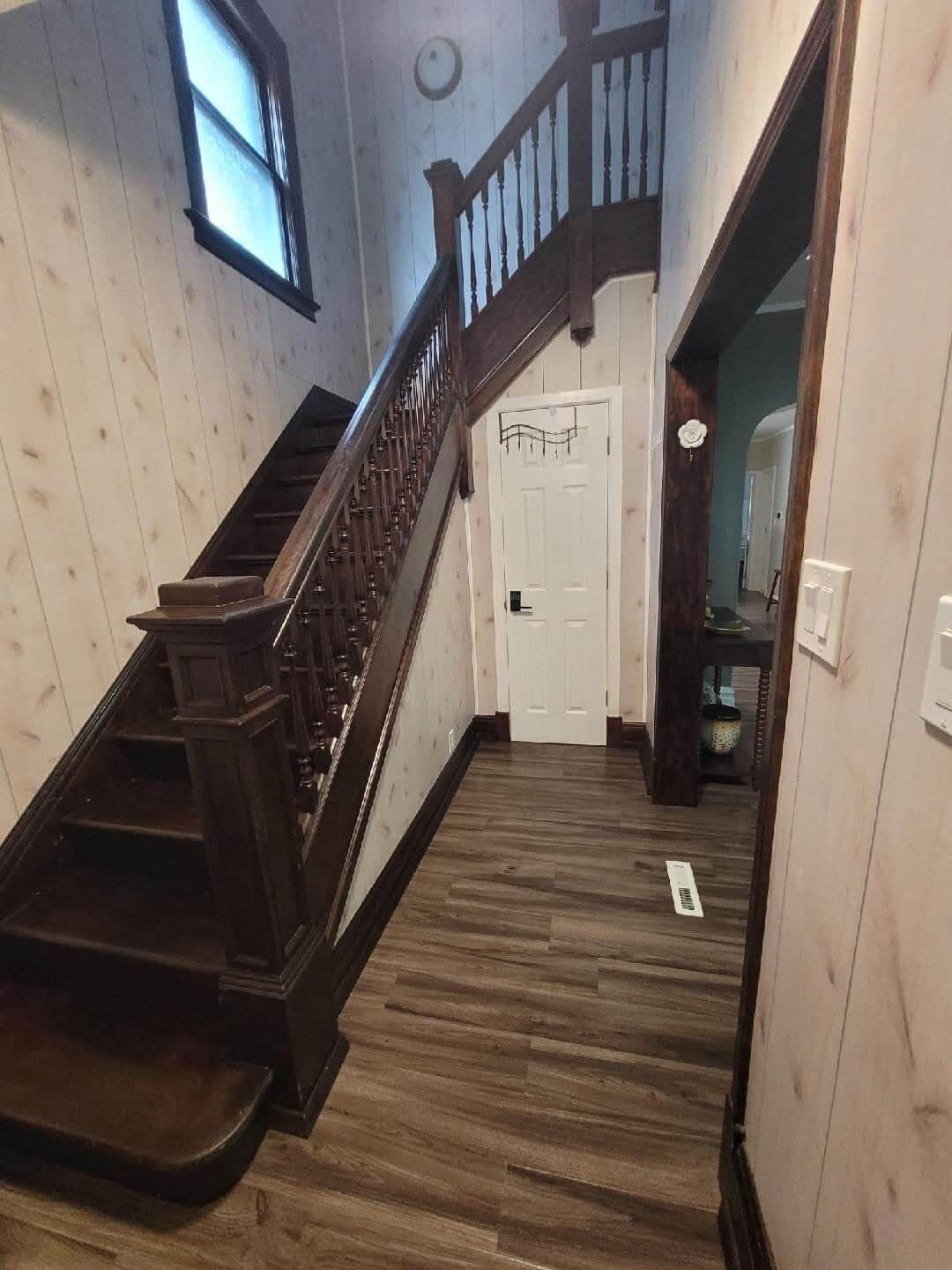 Un escalier en bois, doté d’une rampe, mène à une porte blanche.
