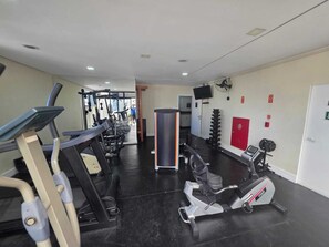 A gym with cardio machines, weightlifting equipment, and a television on the wall. - Premium Flat - 500m from Ibirapuera Park: Comfort, swimming pool, free parking and leisure facilities. (São Paulo)