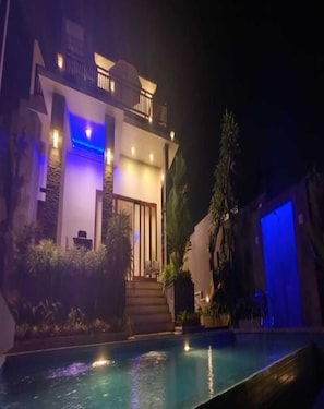 A modern building with a pool at night. - Cozzy The Subahu Villa (Denpasar)