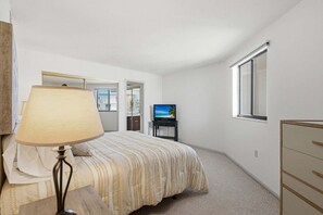 A bedroom with a bed, a TV, a lamp, a dresser, and a window. - Beachfront 2BR Condo with Gulf Views, Screened Lanai & Pickleball | Sleeps 4 (Bonita Springs)