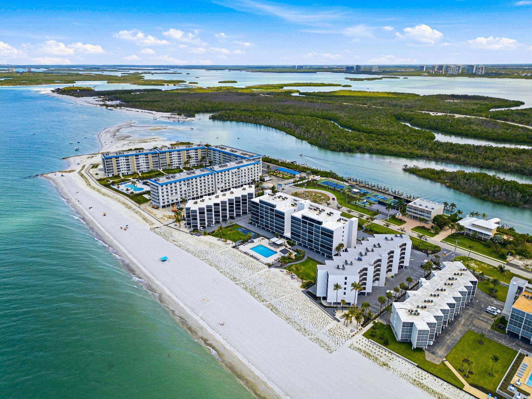 A coastal hotel with multiple buildings, a beach, and a marina.