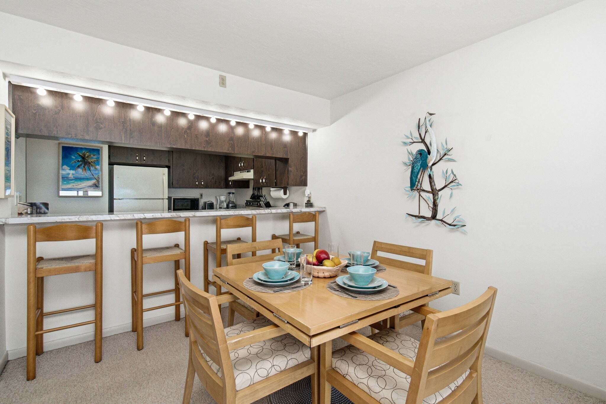 Una cocina compacta con comedor, sillas de madera y una mesa lista para cuatro comensales.