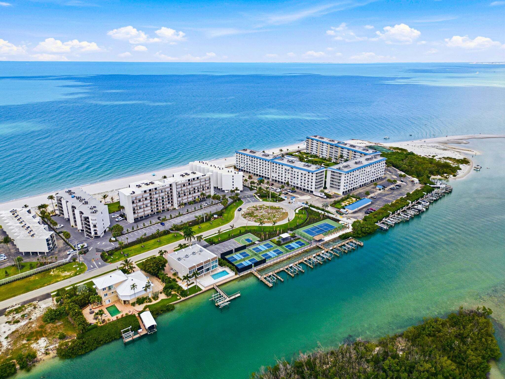 A coastal hotel with multiple buildings, a marina, and a beach.