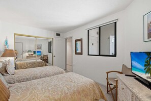 A hotel room with two beds, a desk with a computer, a TV, and a large mirror. - Beachfront 2BR Condo with Gulf Views, Screened Lanai & Pickleball | Sleeps 4 (Bonita Springs)