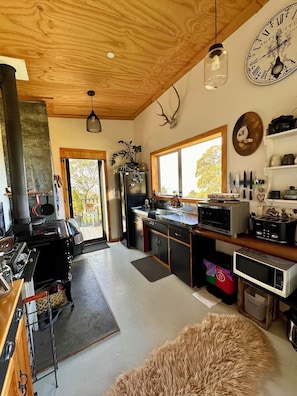 A modern kitchen with a wood ceiling, a large window, and a rustic decor including a clock and antler.