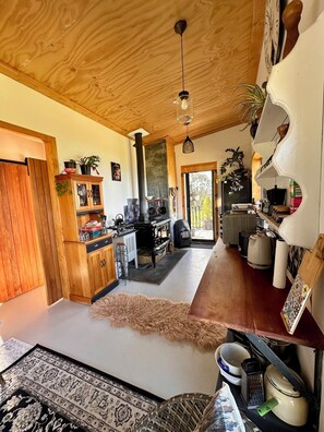 A cozy kitchen with wooden cabinets, a stove, and a dining area with a rug. - Bang for your buck, Sanctuary, Sea & Starry nights, 5 minutes from Gore Bay! (Domett)