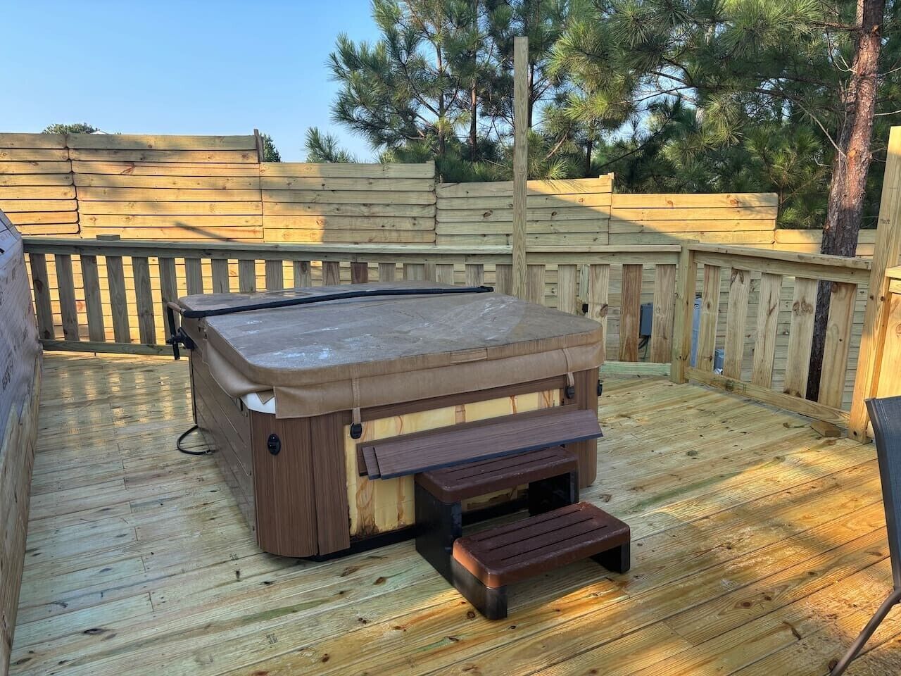 A hot tub on a wooden deck with a wooden fence in the background.