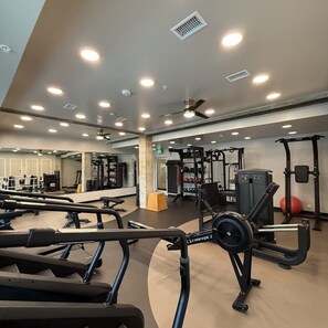 Ein Fitnessstudio mit verschiedenen Trainingsgeräten, darunter Laufbänder und Kraftgeräte.