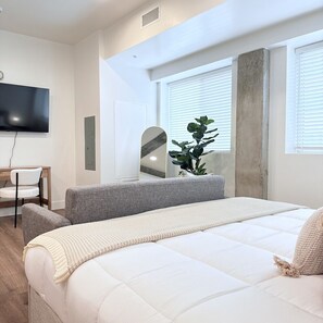 Ein modernes Schlafzimmer mit einem großen Bett, einem Schreibtisch und einem Fernseher.
