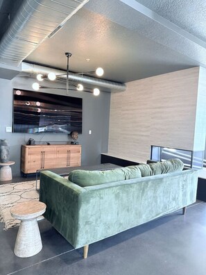 Ein modernes Wohnzimmer mit einem grünen Sofa, einer Holzkabine und einem großen Flachbildfernseher an der Wand.