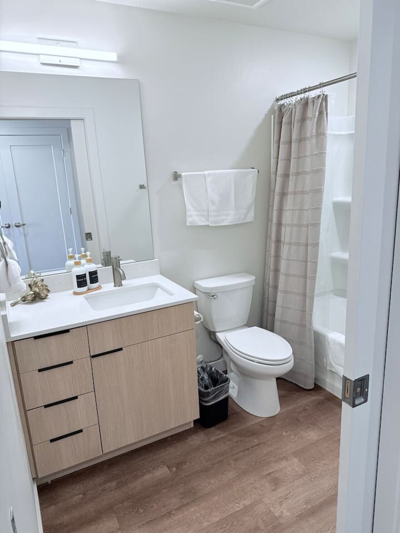 Un baño moderno con lavamanos, inodoro y zona de ducha blancos.