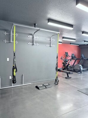 A gym with exercise equipment, including a pull-up bar and a stationary bike. - Downtown SLC Studio | King Bed + Work Space (Salt Lake City)