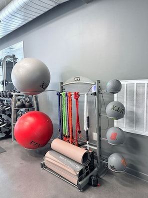 A gym with various exercise equipment including medicine balls, resistance bands, and a foam roller. - Downtown SLC Studio | King Bed + Work Space (Salt Lake City)