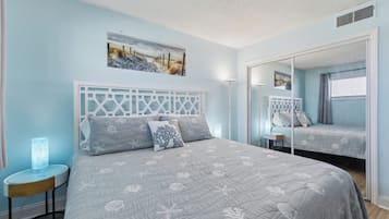 Quarto com cama, mesa de cabeceira, espelho e um quadro na parede.
