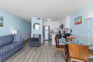 A compact living space with a sofa, armchair, dining table, and kitchenette. - 0704 Beach Life-Free Activities Included (Carolina Beach)
