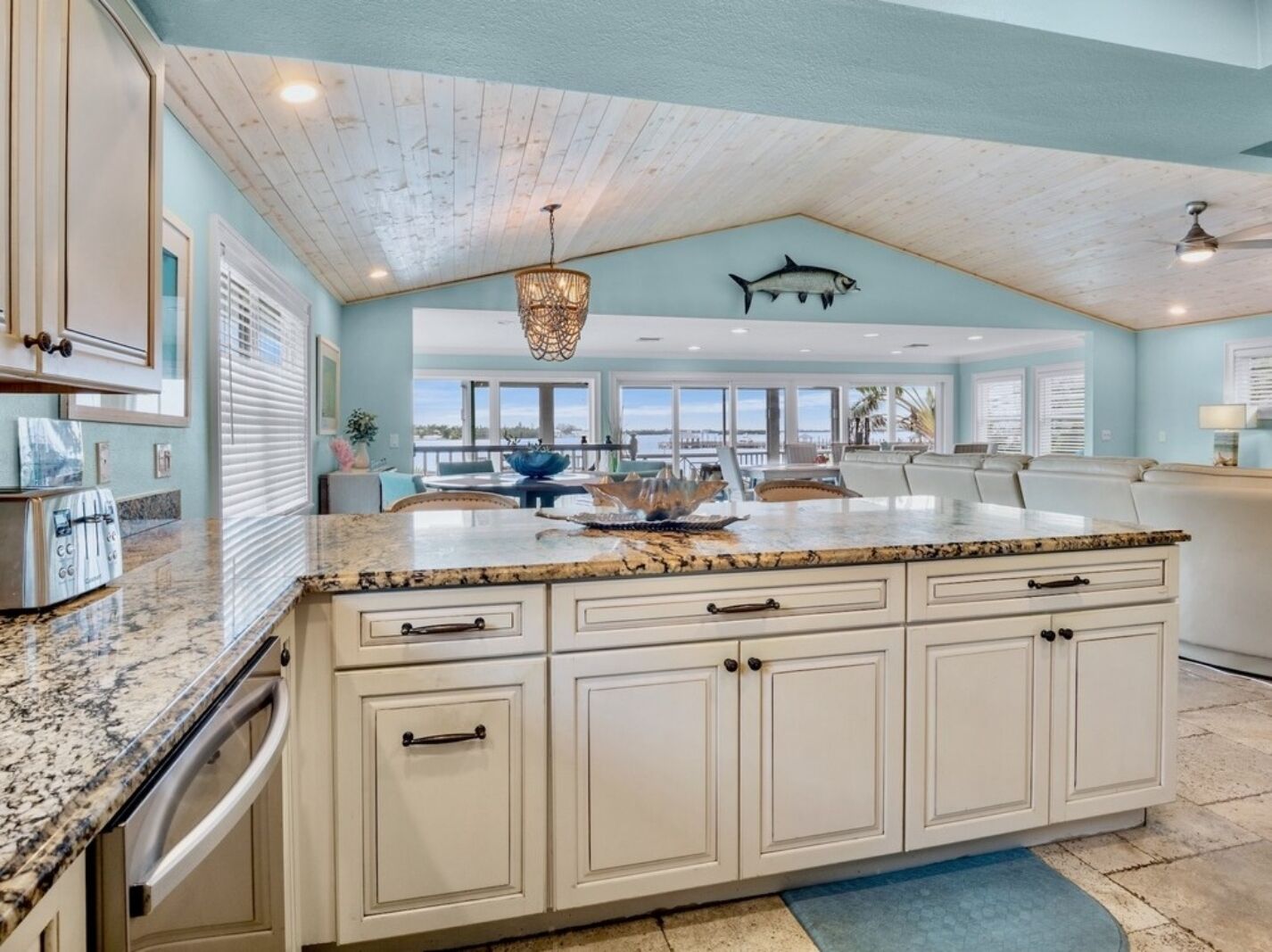 A kitchen with a large island, white cabinetry, and a view to the outside.