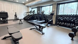 Ein Fitnessraum mit Laufbändern, einer Bank und Kurzhanteln.
