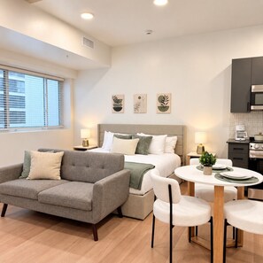 Une chambre d’hôtel moderne équipée d’un lit, d’un canapé, d’une table à manger avec des chaises et d’une kitchenette.