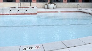 Ein Schwimmbad neben einem Gebäude mit Backsteinfassade, großen Fenstern und einem Schild mit Poolregeln.